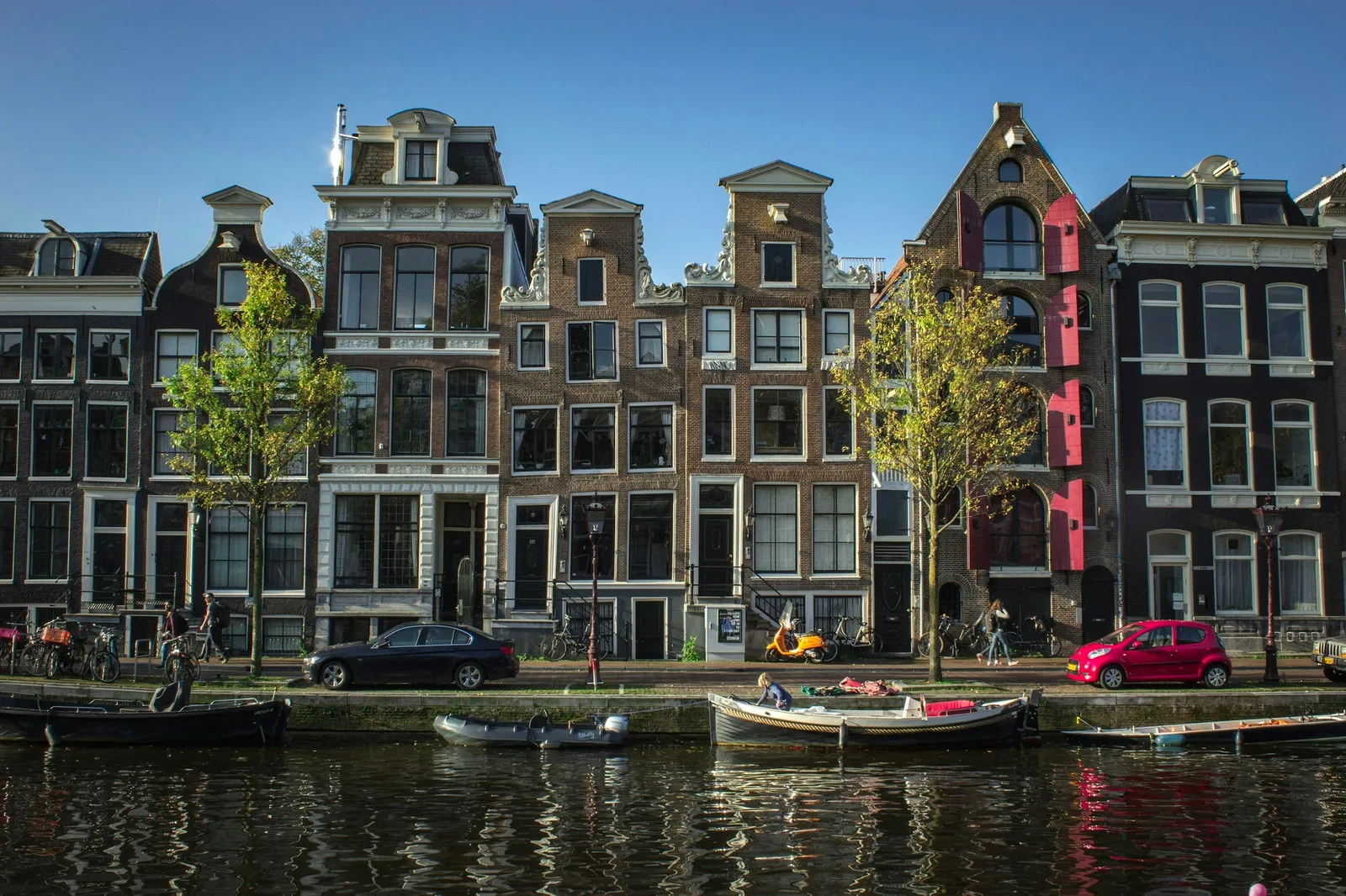 Rangée de hautes maisons de canal en brique à pignons sculptés le long d'un canal d'Amsterdam, par beau temps